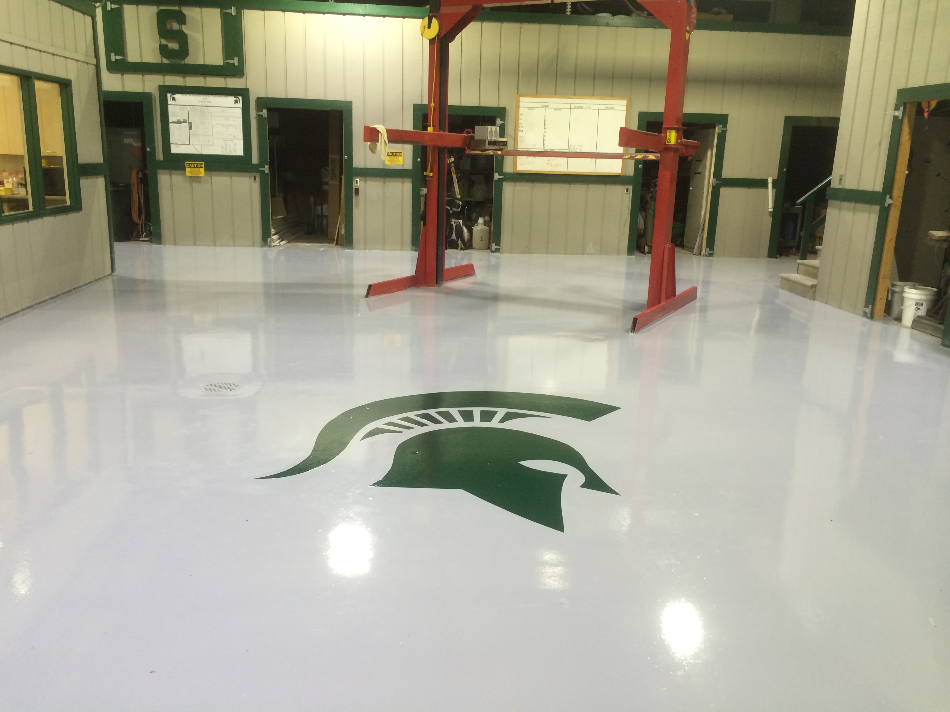 Image of epoxy floor with MSU Spartan logo and red lift in thebackground.